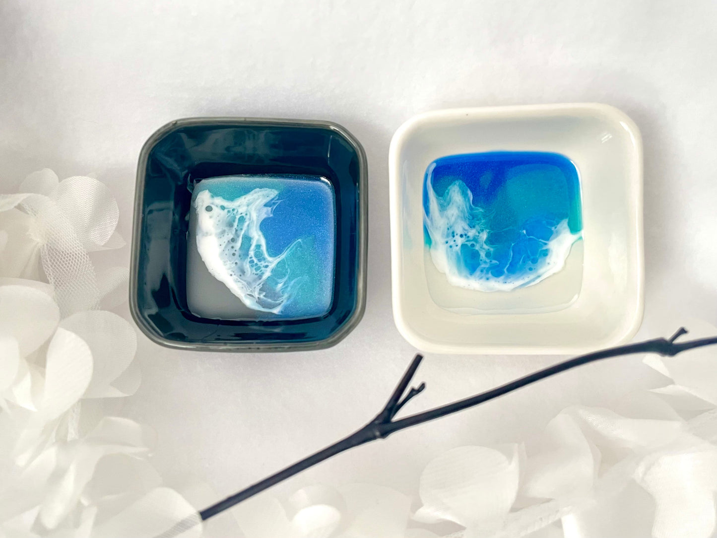 Two square ceramic ring dishes with resin ocean waves. One is balack and one is white.