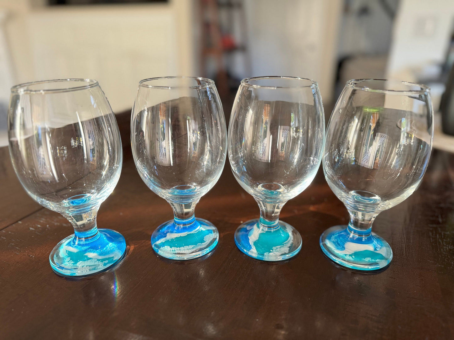 Tulip shaped beer glasses, decoration with resin ocean waves on the base of the glasses. The waves are blue, turquoise, and white foam.