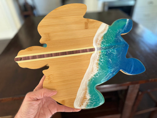 Sea Turtle shaped wood cutting board with a blue and turquoise resin ocean wave with white foam crashing over the back.