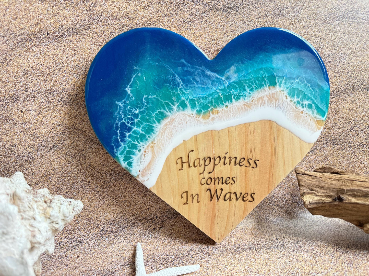 Coastal wall decor wooden heart with ocean waves and &quot;Happiness comes in Waves&quot; engraved in the sand area of the beach scene.